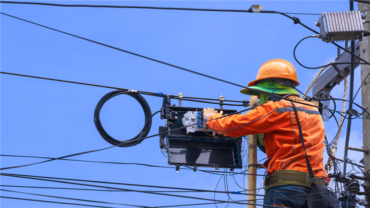 hardhatted person on a ladder installing a splitter box